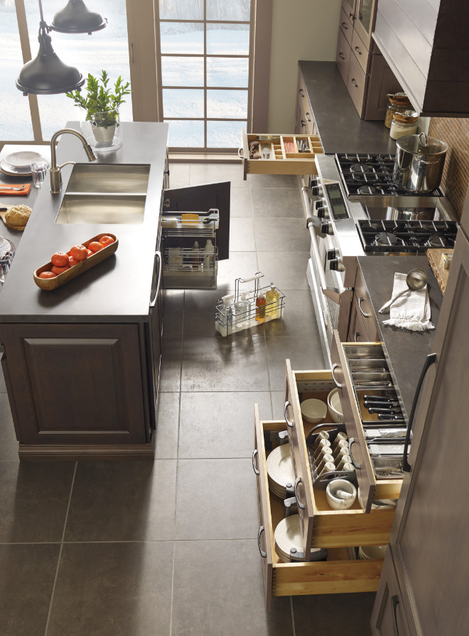 Example of a large transitional galley slate floor enclosed kitchen design with an undermount sink, shaker cabinets, brown cabinets, quartz countertops, beige backsplash, mosaic tile backsplash, stainless steel appliances and an island