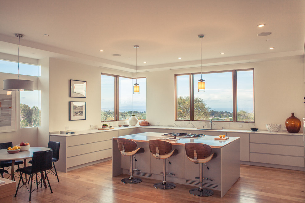 This is an example of a contemporary u-shaped eat-in kitchen in Los Angeles with flat-panel cabinets, grey cabinets, medium hardwood floors and with island.