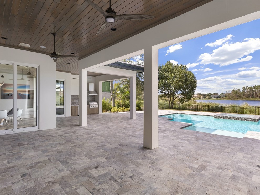 Inspiration for a large transitional backyard patio in Orlando with an outdoor kitchen, tile and a roof extension.