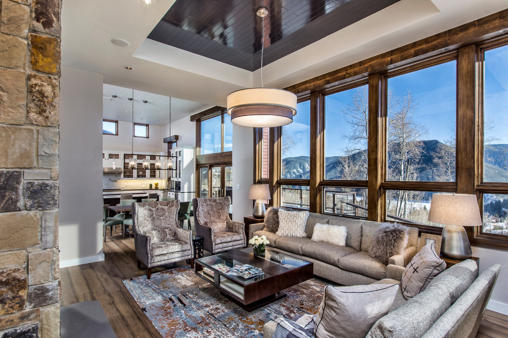 Inspiration for an expansive country open concept family room in Denver with beige walls, light hardwood floors, a standard fireplace, a stone fireplace surround and brown floor.