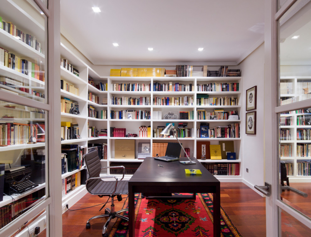 This is an example of a mid-sized transitional study room in Madrid with white walls, dark hardwood floors, no fireplace and a freestanding desk.