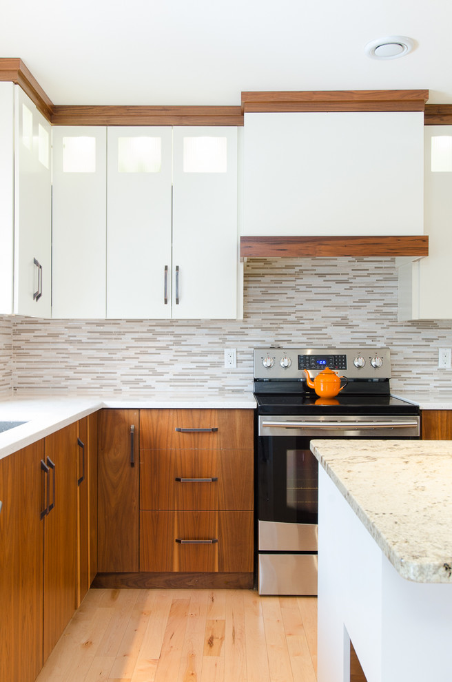 Mid-sized transitional l-shaped light wood floor eat-in kitchen photo with an undermount sink, flat-panel cabinets, white cabinets, granite countertops, multicolored backsplash, mosaic tile backsplash, stainless steel appliances and an island