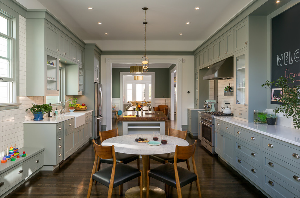 Inspiration for a traditional separate kitchen in San Francisco with a farmhouse sink, shaker cabinets, white splashback, subway tile splashback, stainless steel appliances, dark hardwood floors, with island and green cabinets.