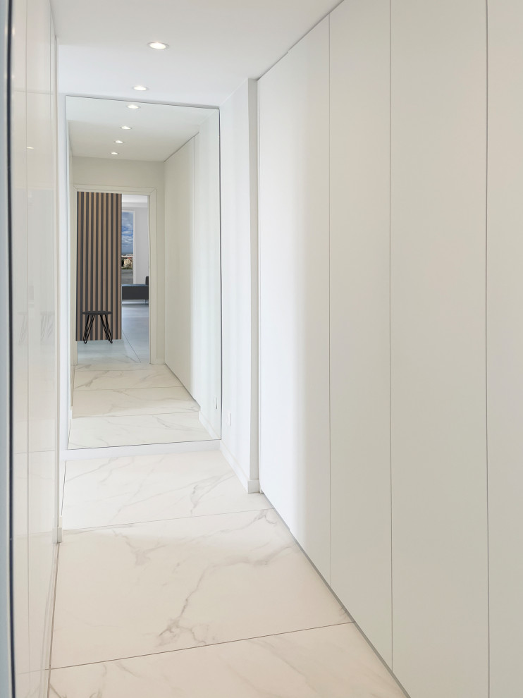This is an example of a large modern gender-neutral storage and wardrobe in Bordeaux with flat-panel cabinets, white cabinets, marble floors and white floor.