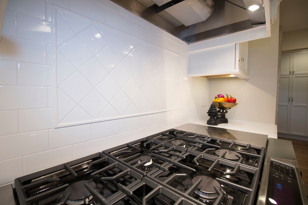 Inspiration for a huge transitional medium tone wood floor open concept kitchen remodel with an undermount sink, shaker cabinets, white cabinets, marble countertops, white backsplash, ceramic backsplash, stainless steel appliances and two islands