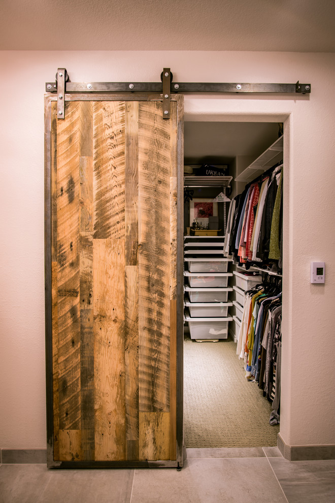This is an example of a mid-sized country gender-neutral walk-in wardrobe in Denver with flat-panel cabinets and carpet.