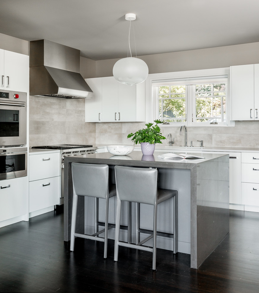 Photo of a contemporary l-shaped kitchen in Seattle with flat-panel cabinets, white cabinets, grey splashback, stainless steel appliances, dark hardwood floors, with island and brown floor.