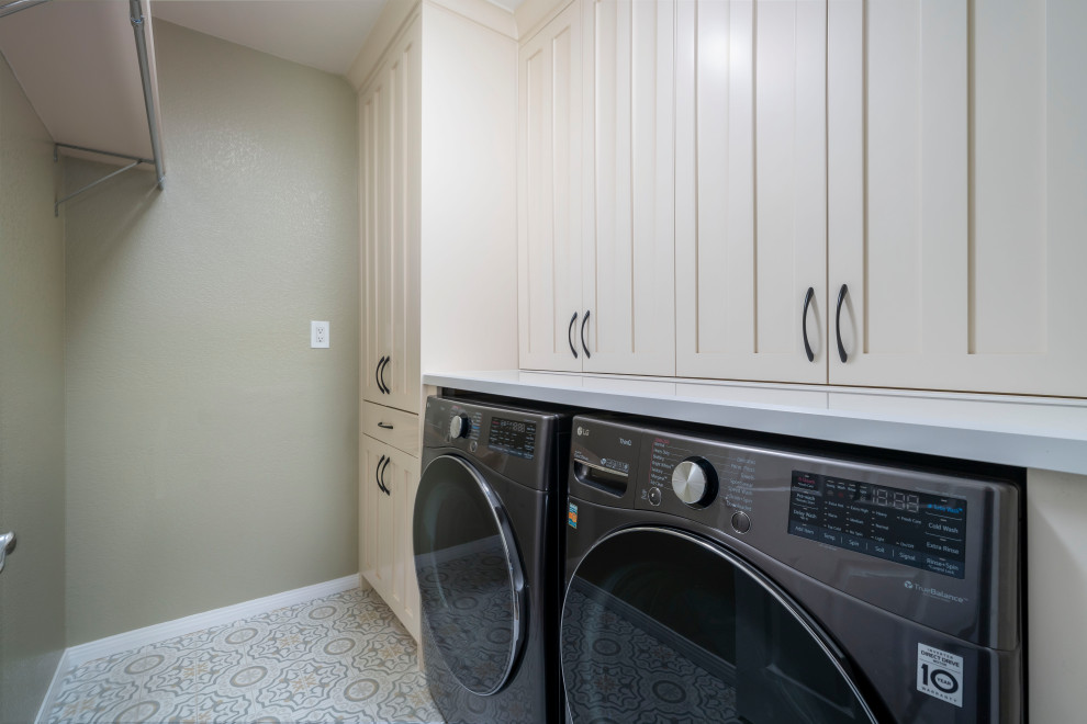 Immagine di una sala lavanderia stile americano di medie dimensioni con ante con bugna sagomata, ante beige, top in quarzo composito, pareti verdi, pavimento in gres porcellanato, lavatrice e asciugatrice affiancate, pavimento beige e top bianco