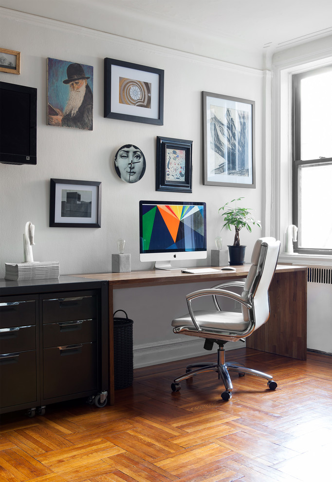 Inspiration for an eclectic home office in New York with white walls and medium hardwood floors.