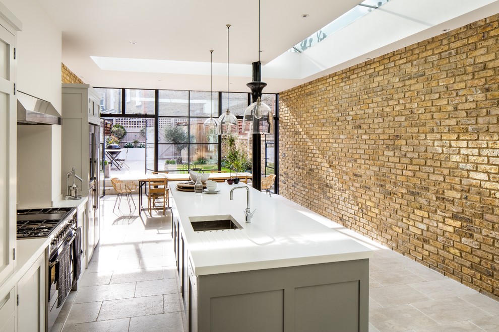 Inspiration for a mid-sized contemporary single-wall eat-in kitchen in London with an integrated sink, shaker cabinets, grey cabinets, solid surface benchtops, glass sheet splashback, stainless steel appliances, limestone floors and with island.