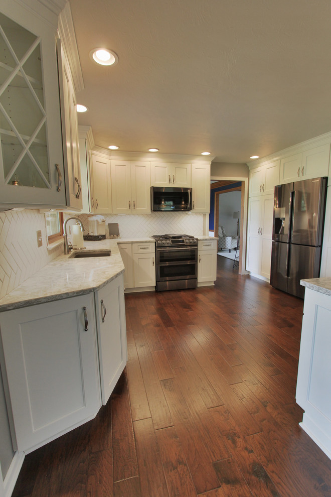 Eat-in kitchen - mid-sized l-shaped dark wood floor eat-in kitchen idea with an undermount sink, white cabinets, quartzite countertops, white backsplash, ceramic backsplash, stainless steel appliances and no island