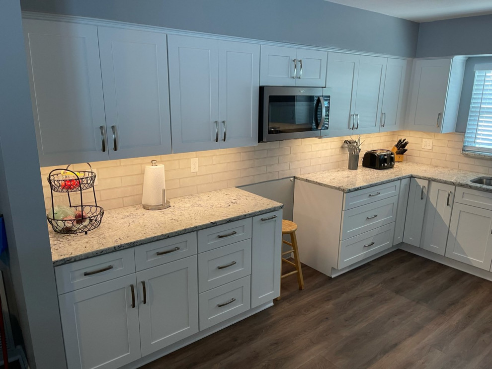 This is an example of a mid-sized transitional u-shaped kitchen pantry in Tampa with white cabinets and granite benchtops.