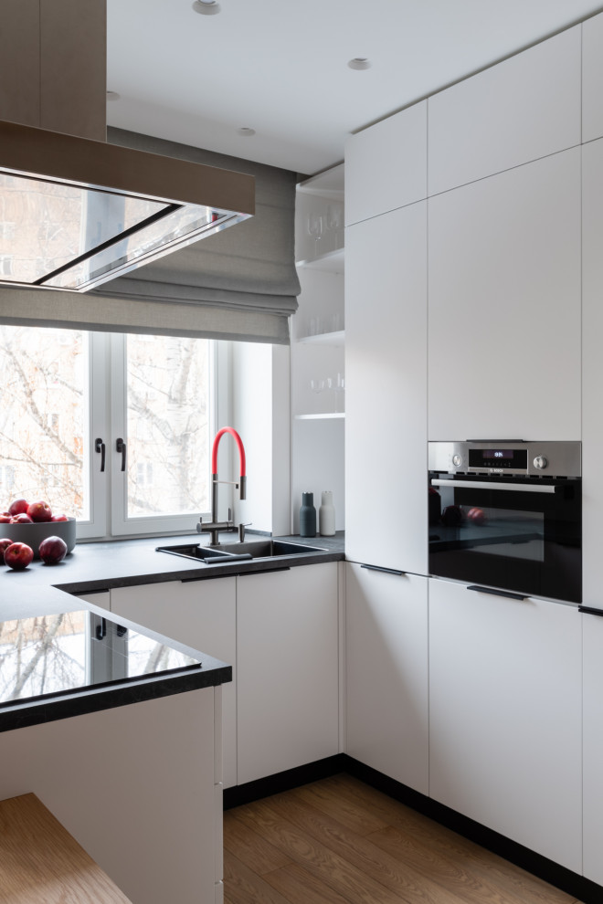 Idee per una cucina minimal di medie dimensioni con lavello sottopiano, ante lisce, ante bianche e pavimento in legno massello medio