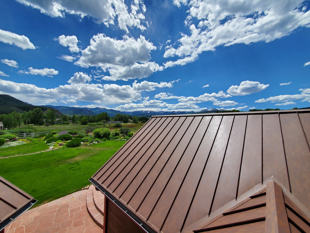This is an example of a country house exterior in Denver with a gable roof and a metal roof.