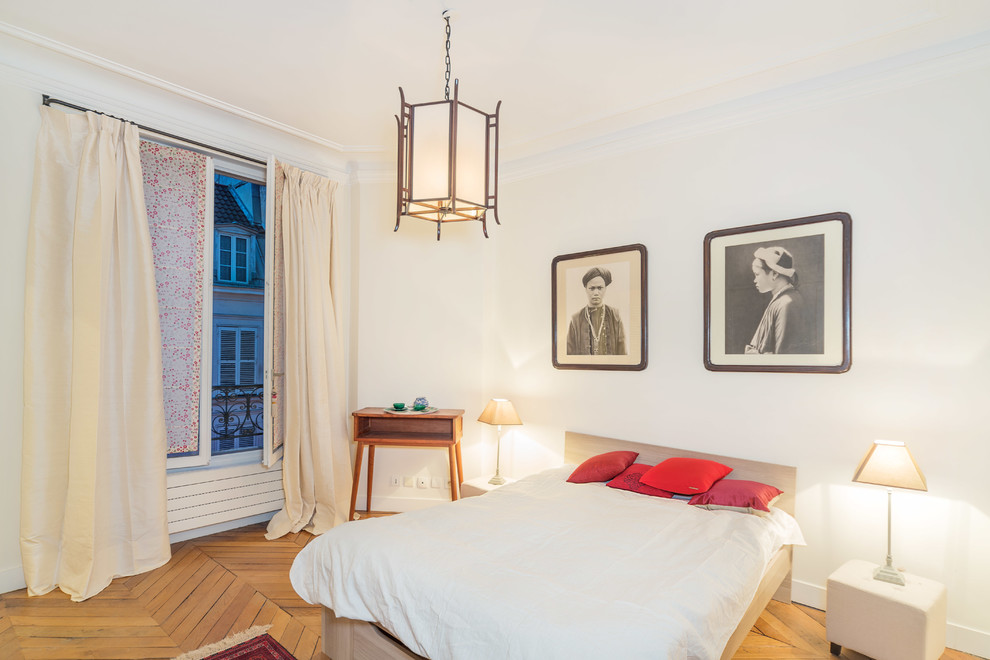 This is an example of a mid-sized transitional master bedroom in Paris with white walls and medium hardwood floors.