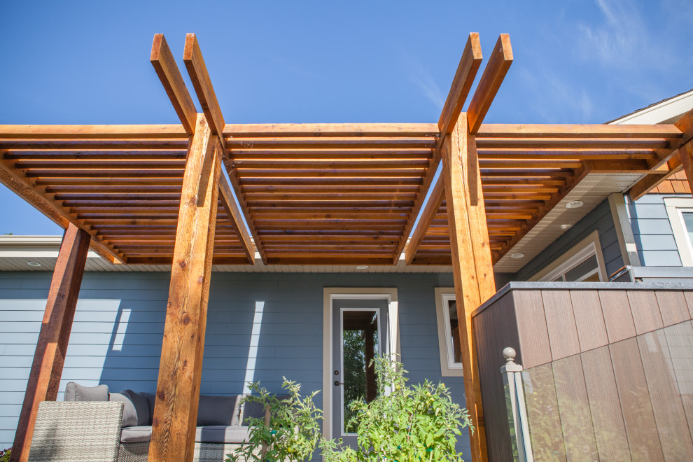 Example of a mid-sized trendy backyard deck design in Calgary with a pergola