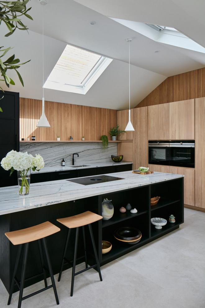 Example of a large trendy open concept kitchen design in London with a drop-in sink, flat-panel cabinets, black cabinets, quartzite countertops, multicolored backsplash, black appliances, an island and multicolored countertops