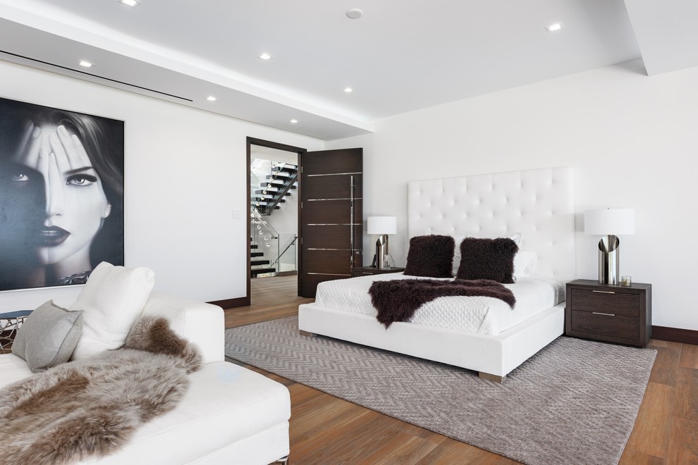Inspiration for a contemporary medium tone wood floor and brown floor bedroom remodel in Miami with white walls
