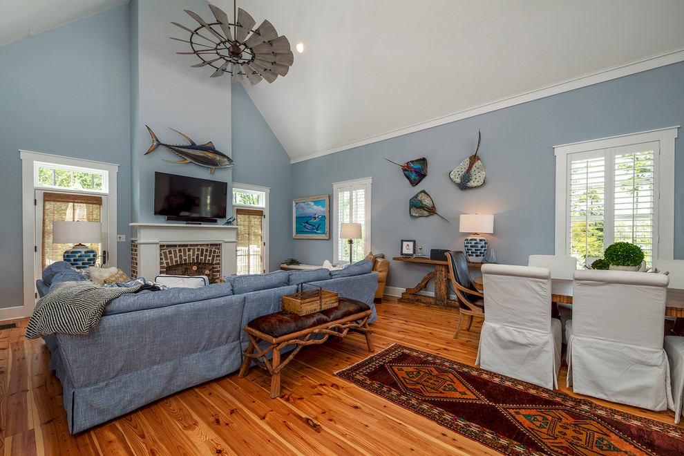 Small traditional guest bedroom in Raleigh with blue walls, light hardwood floors, a standard fireplace, a wood fireplace surround and brown floor.