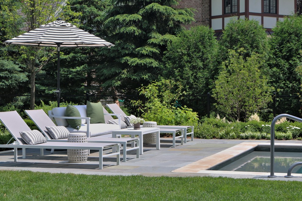 Mid-sized traditional backyard rectangular pool in Chicago with natural stone pavers.