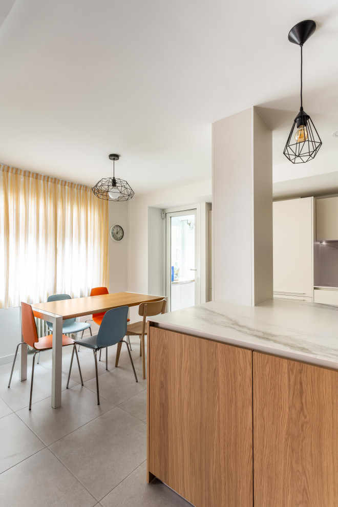 Large modern single-wall open plan kitchen in Madrid with a submerged sink, flat-panel cabinets, light wood cabinets, marble worktops, white splashback, marble splashback, integrated appliances, cement flooring, an island, grey floors and white worktops.