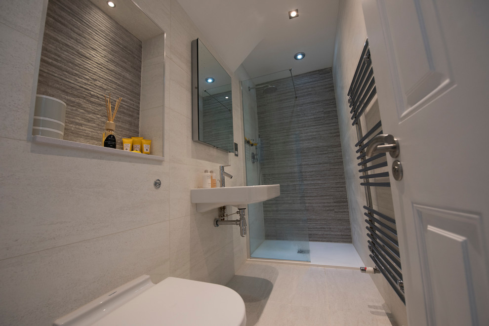 This is an example of a small contemporary 3/4 bathroom in London with an open shower, a wall-mount toilet, beige tile, ceramic tile, beige walls, ceramic floors and a wall-mount sink.