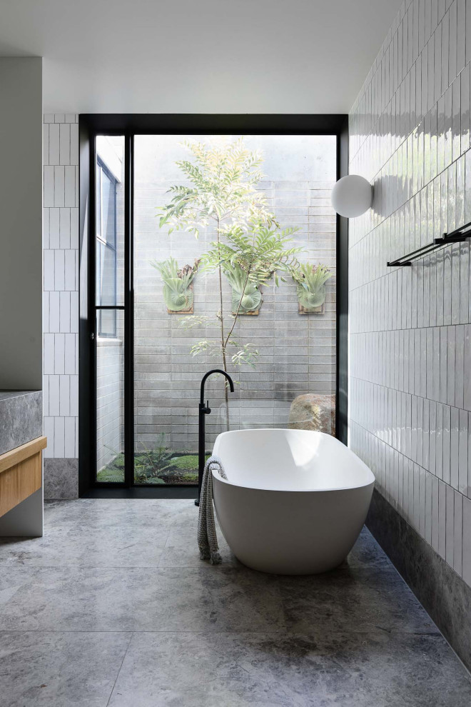 Large contemporary master bathroom in Melbourne with flat-panel cabinets, grey cabinets, a freestanding tub, gray tile, white tile, grey floor, grey benchtops and a floating vanity.
