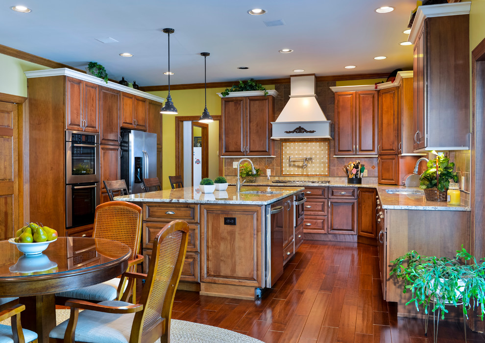 Example of a large transitional u-shaped medium tone wood floor eat-in kitchen design with beaded inset cabinets, medium tone wood cabinets, granite countertops, beige backsplash, mosaic tile backsplash, stainless steel appliances and an island