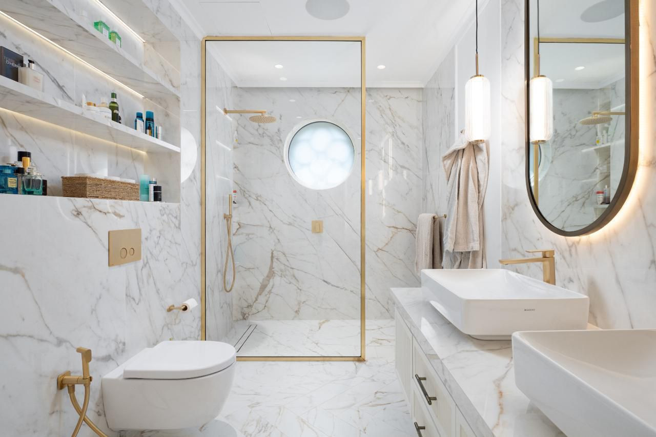A family bathroom in London with a Mr and Mrs sink designed in a very luxurious colour finish of white and gold throughout with a marble effect stone.