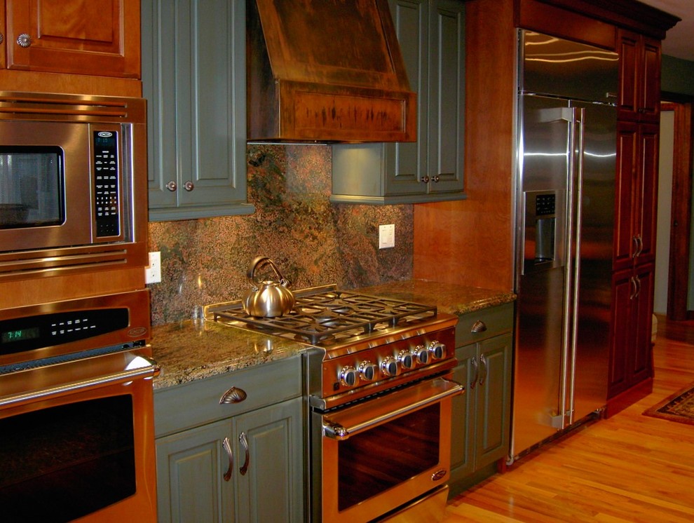 This is an example of a mid-sized arts and crafts u-shaped eat-in kitchen in New York with raised-panel cabinets, green cabinets, granite benchtops, multi-coloured splashback, stone slab splashback, stainless steel appliances, light hardwood floors, brown floor and multi-coloured benchtop.