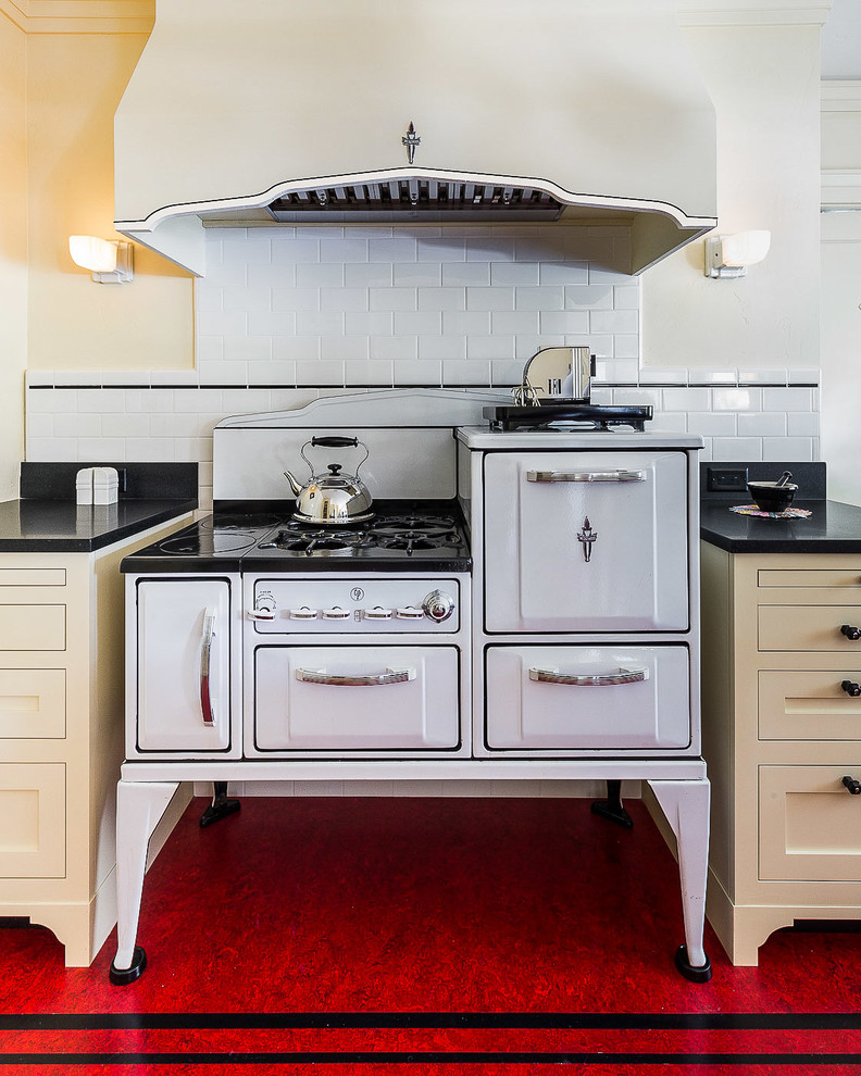 This is an example of a mid-sized arts and crafts l-shaped kitchen pantry in Other with an undermount sink, shaker cabinets, yellow cabinets, granite benchtops, white splashback, ceramic splashback, white appliances, linoleum floors, with island, red floor and black benchtop.