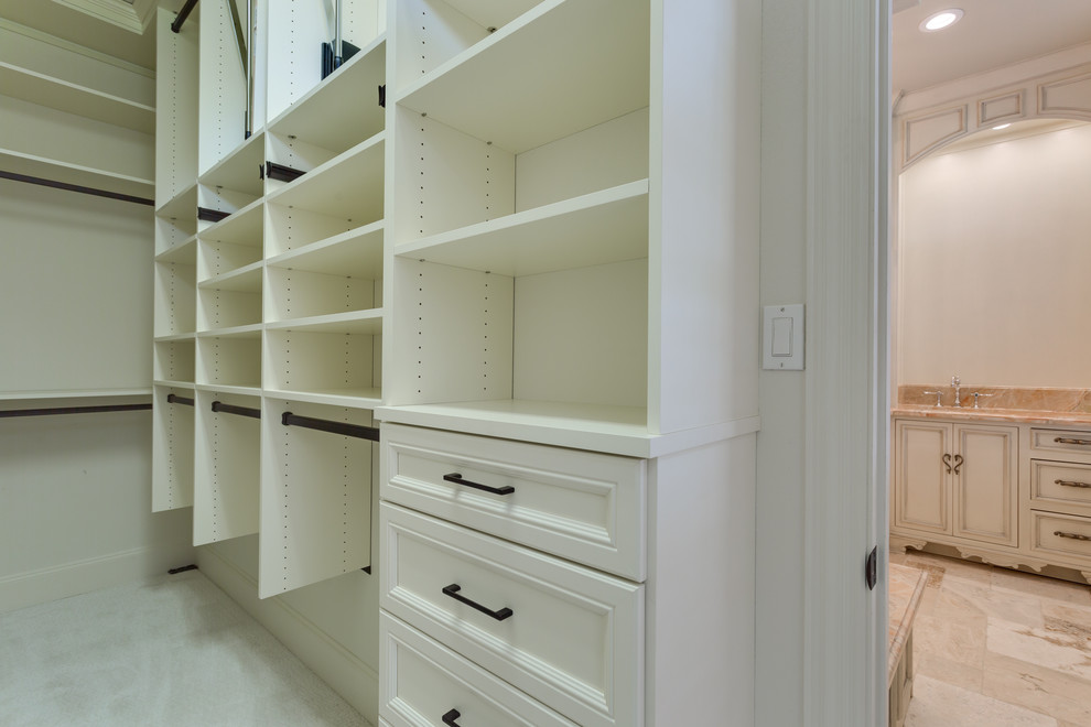 Inspiration for a mid-sized traditional gender-neutral walk-in wardrobe in Dallas with raised-panel cabinets, white cabinets, carpet and white floor.