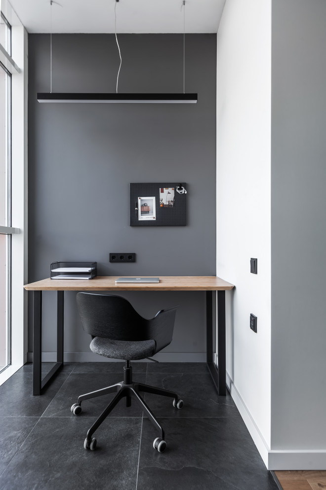 Modelo de despacho pequeño con paredes grises, suelo de baldosas de porcelana, escritorio independiente y suelo negro