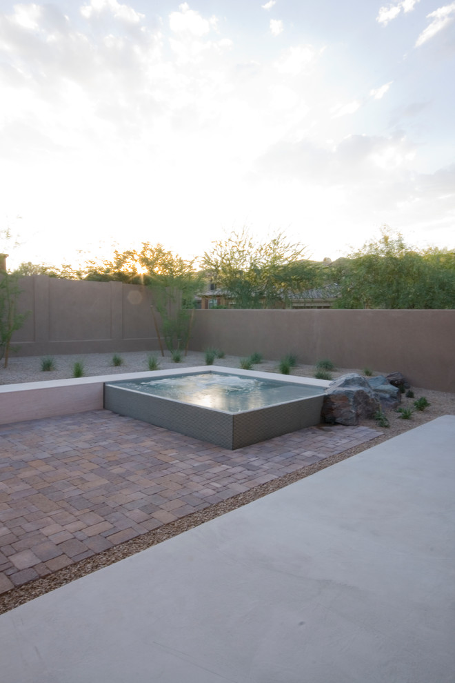 Photo of a small modern backyard custom-shaped infinity pool in Phoenix with a hot tub and brick pavers.