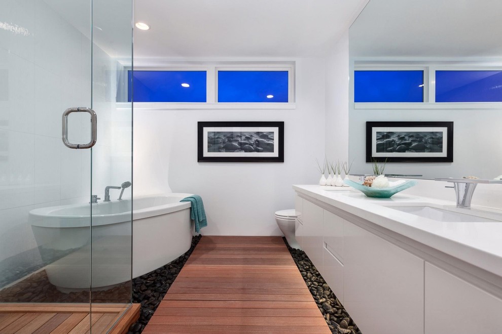 Contemporary bathroom in Vancouver with an undermount sink, flat-panel cabinets, white cabinets, a freestanding tub and white tile.