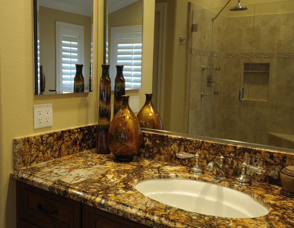 Photo of a large traditional master bathroom in Orange County with an undermount sink, recessed-panel cabinets, dark wood cabinets, granite benchtops, a freestanding tub, an alcove shower, a one-piece toilet, beige tile, ceramic tile, beige walls and travertine floors.