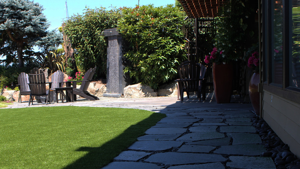 This is an example of a large transitional partial sun backyard stone formal garden in Seattle for summer.