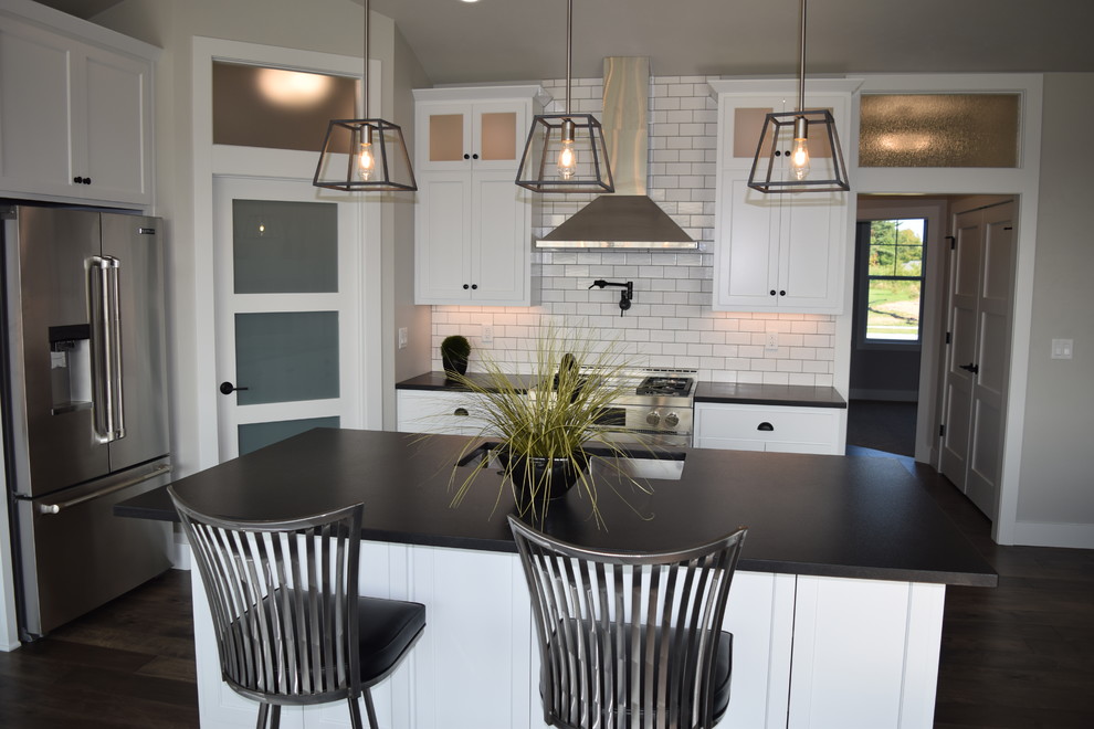 Inspiration for a large l-shaped dark wood floor and brown floor open concept kitchen remodel with an undermount sink, recessed-panel cabinets, white cabinets, granite countertops, white backsplash, ceramic backsplash, stainless steel appliances and an island