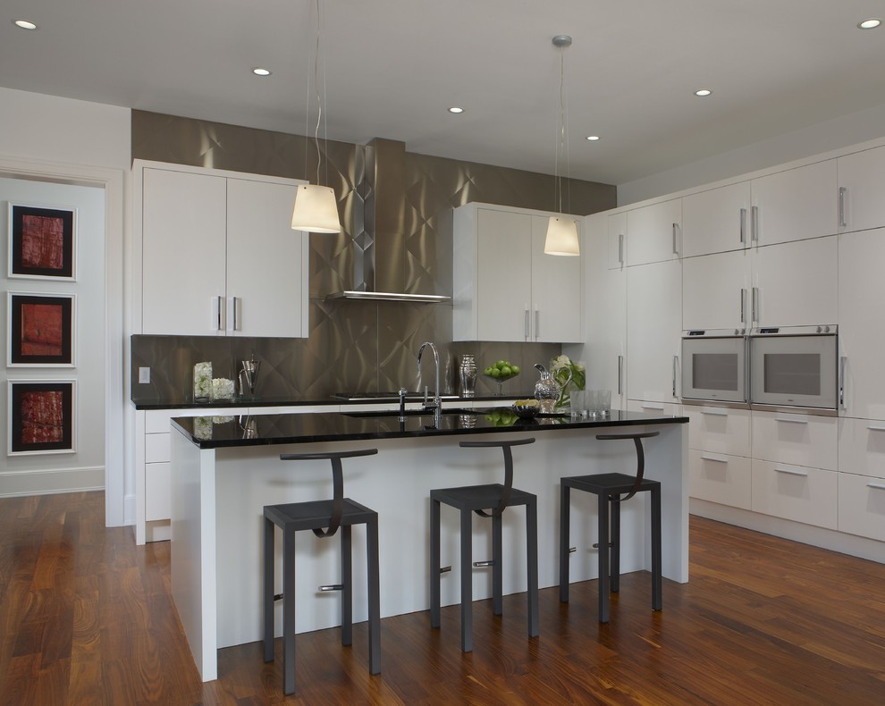 This is an example of a contemporary galley kitchen in Detroit with metallic splashback, metal splashback, white cabinets, flat-panel cabinets and an undermount sink.