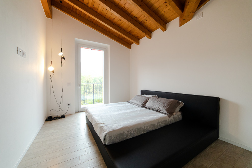 Imagen de dormitorio tipo loft y blanco y madera minimalista de tamaño medio con paredes blancas, suelo de baldosas de porcelana, suelo gris y vigas vistas