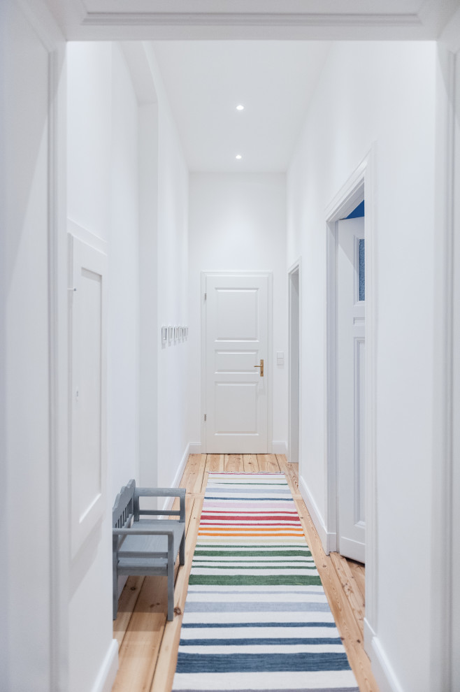 На фото: коридор среднего размера в современном стиле с белыми стенами, деревянным полом и коричневым полом