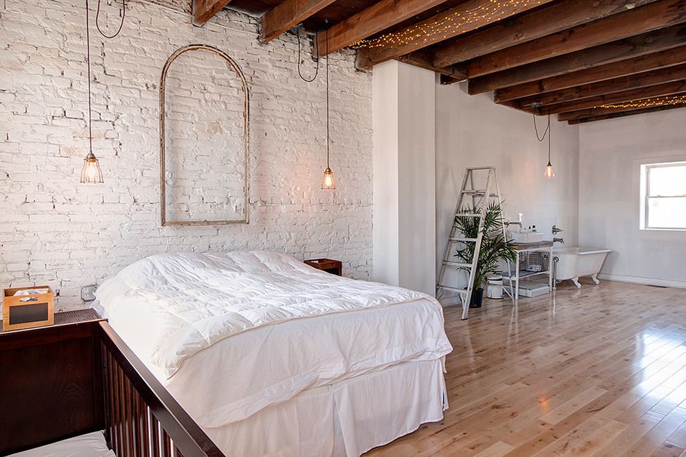 Large industrial loft-style bedroom in Philadelphia with white walls and light hardwood floors.