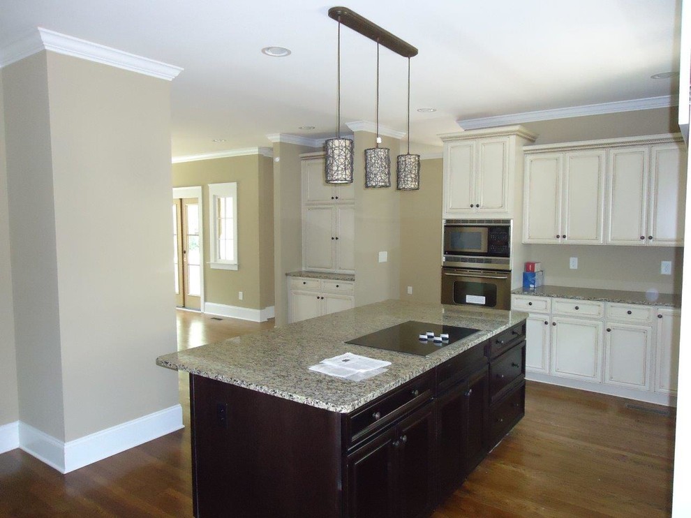 Mid-sized traditional u-shaped open plan kitchen in Birmingham with a drop-in sink, flat-panel cabinets, white cabinets, granite benchtops, stainless steel appliances, dark hardwood floors and no island.