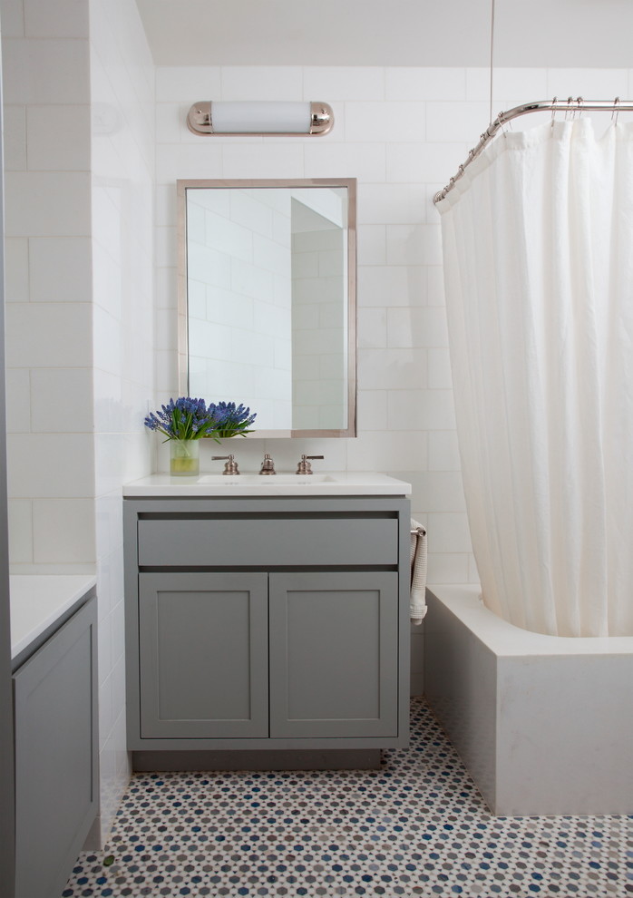 Photo of a small transitional bathroom in New York with an integrated sink, shaker cabinets, grey cabinets, a shower/bathtub combo, white tile and mosaic tile floors.