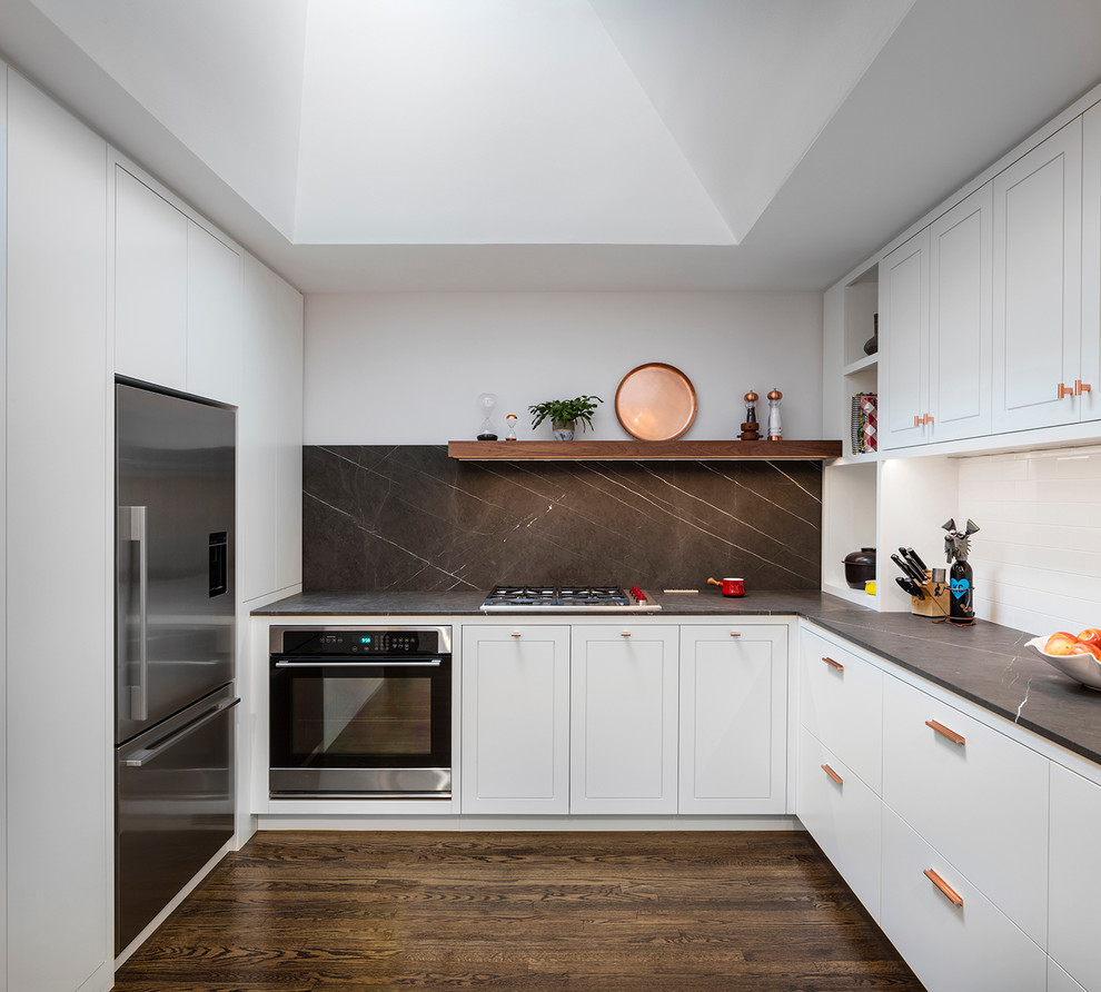 Inspiration for a mid-sized contemporary l-shaped kitchen in Kansas City with white cabinets, marble benchtops, black splashback, stone slab splashback, stainless steel appliances and dark hardwood floors.