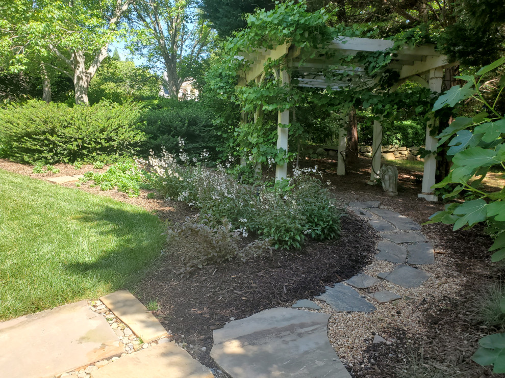 This is an example of a large classic back xeriscape full sun garden in Other with a raised bed and natural stone paving.
