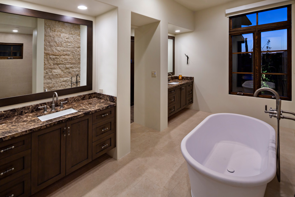 Design ideas for a mid-sized transitional master bathroom in Phoenix with recessed-panel cabinets, brown cabinets, a freestanding tub, white walls, travertine floors, a drop-in sink, marble benchtops, beige floor, brown benchtops, a double vanity and a built-in vanity.