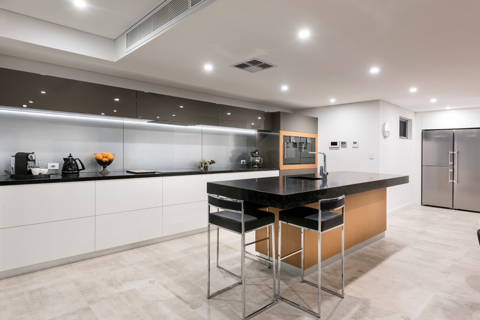 Design ideas for a large contemporary galley open plan kitchen in Perth with an undermount sink, flat-panel cabinets, medium wood cabinets, quartz benchtops, grey splashback, glass sheet splashback, black appliances, porcelain floors and with island.