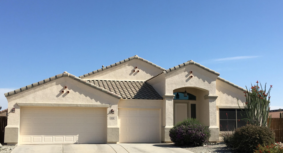 This is an example of a mid-sized one-storey stucco beige house exterior in Phoenix with a hip roof and a tile roof.