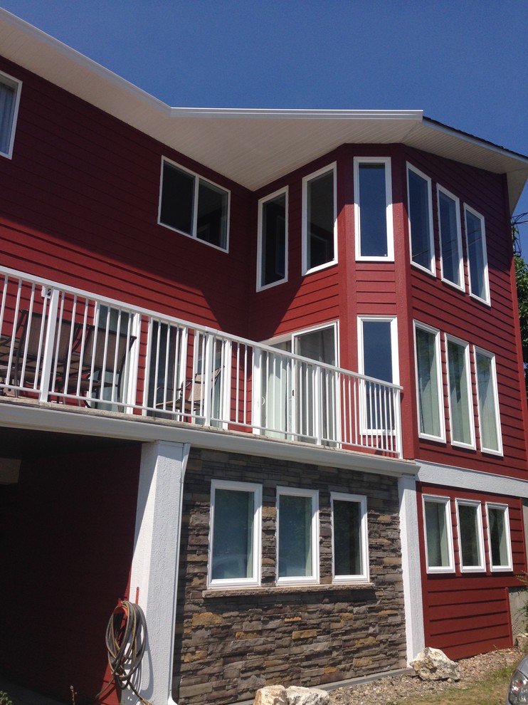 This is an example of a large contemporary three-storey red exterior in Vancouver with concrete fiberboard siding and a gable roof.